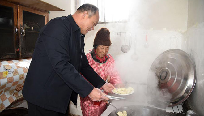 Lokalbeamter hilft gealterten Dorfbewohnern beim Kochen für das Frühlingsfest in Rizhao